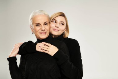 Olgun bir kadın, sevgi saçan yetişkin kızıyla sıcak bir kucaklaşmadan hoşlanır..