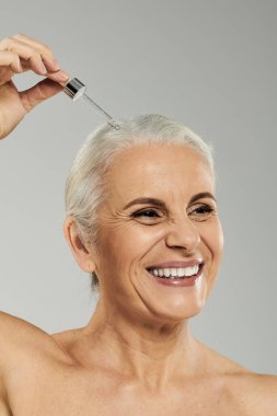 A mature woman shares a joyful moment while applying a product. clipart