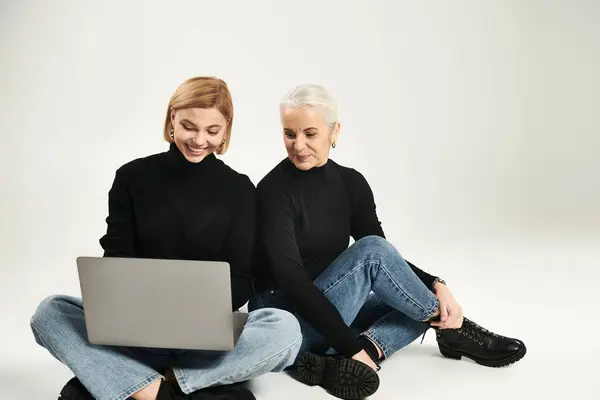 stock image A woman and her daughter share a joyful moment, engaging with a laptop together.