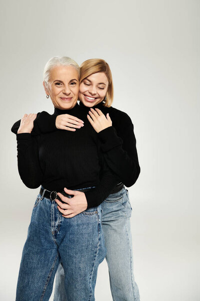 Зрелая женщина радостно обнимает свою взрослую дочь в теплых объятиях.