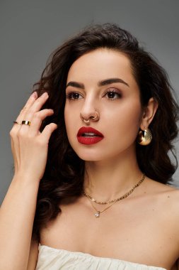 Güzel genç bir kadın mücevherlerini sergiliyor, kendine güveni ve cazibesi yayılıyor..