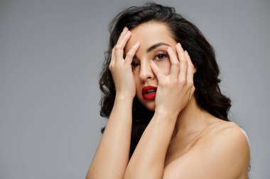 Güzel bir kadın zarif bir şekilde gri zeminde poz verir..