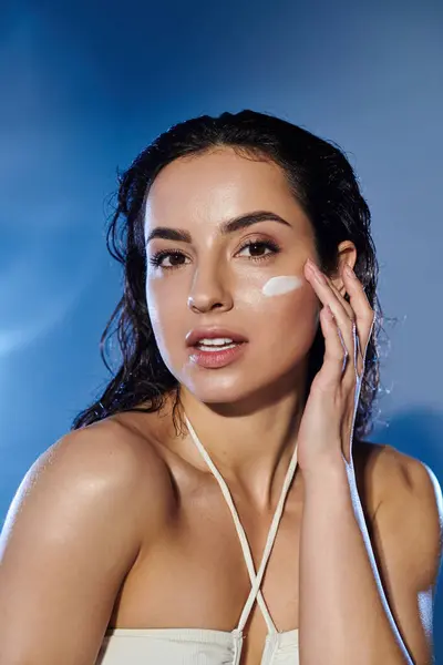 Stock image A young woman applies skincare on her face with confidence and grace.