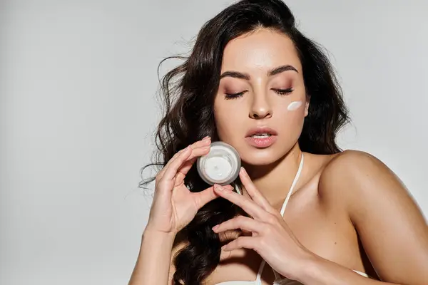 stock image A young woman showcases her skincare routine on a colorful background.