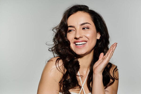 Joyous woman poses confidently on white backdrop.
