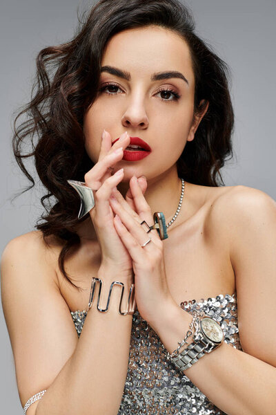 Стильная женщина элегантно демонстрирует свои украшения, играя в позу.