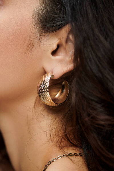 A young woman showcases her jewelry with a colorful backdrop.