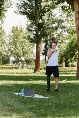 Dövmeli genç adam Green Park 'ta çalışıyor, online fitness dersi alıyor.
