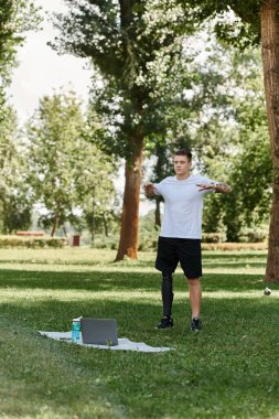 Yeşil Park 'ta çalışan dövmeli adam, online fitness dersi alıyor.