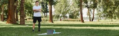 Yeşil Park 'ta çalışan protez bacaklı dövmeli genç bir adam online fitness dersi alıyor.