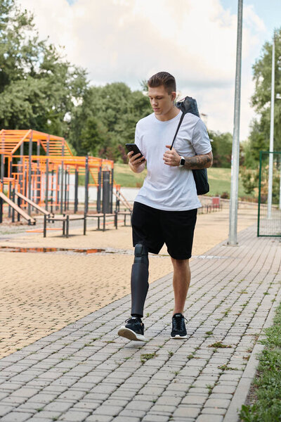 Молодой человек с татуировками прогуливается по парку, проверяя телефон, принимая свое уникальное путешествие.