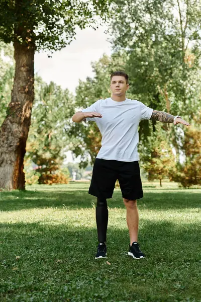 stock image Tattooed young man with artificial leg exercising outdoors in a sunny park