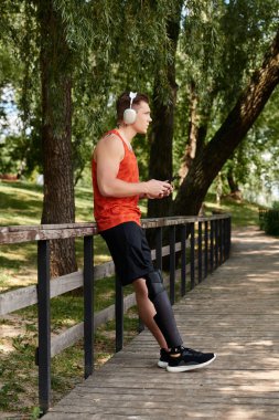 Yapay bacaklı, akıllı telefon kullanan genç bir sporcu parkın çevresini sarmış durumda.