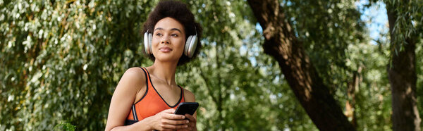 A young woman using smartphone and listening music in wireless headphones in park
