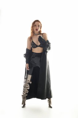 Kendine güvenen bir kadın, parlak bir arkaplan karşısında şık giyinir..