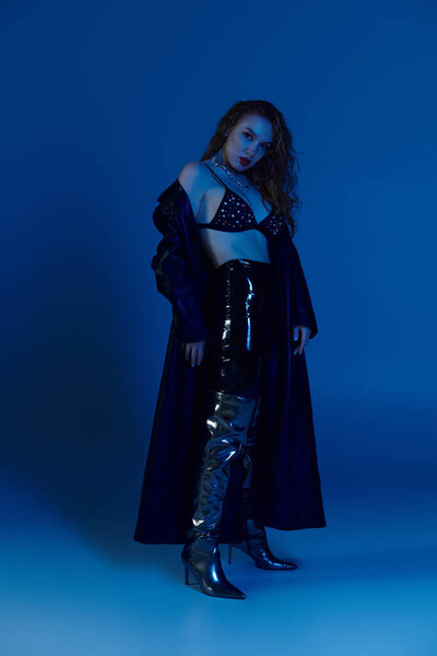 Уверенная в себе женщина позирует на ярком голубом фоне..