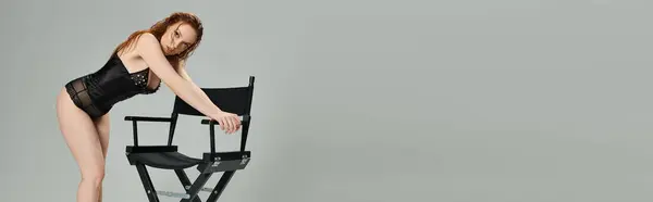 stock image A stylish woman showcases her fashion sense while interacting with a chair.