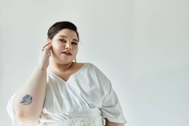 A beautiful plus size bride showcases her wedding dress and earrings, radiating elegance and grace. clipart