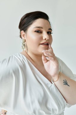 Dalgalı beyaz bir elbise ve parlak küpeler içinde güzel, iri cüsseli bir gelin zarafet saçar..