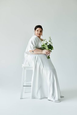 Dalgalı beyaz elbisesiyle genç ve güzel bir gelin bir buket tutuyor, neşe ve güven saçıyor..