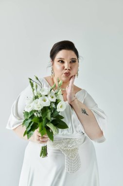 Beyaz elbiseli, kendine güvenen bir gelin, bir buketle neşe içinde poz verir, güzelliğini ve zarafetini gösterir..