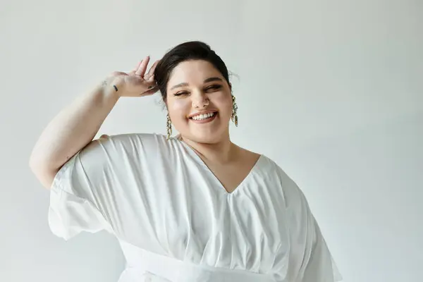 stock image A beautiful plus size bride beams joyfully, adorned in a flowing white dress and elegant earrings.