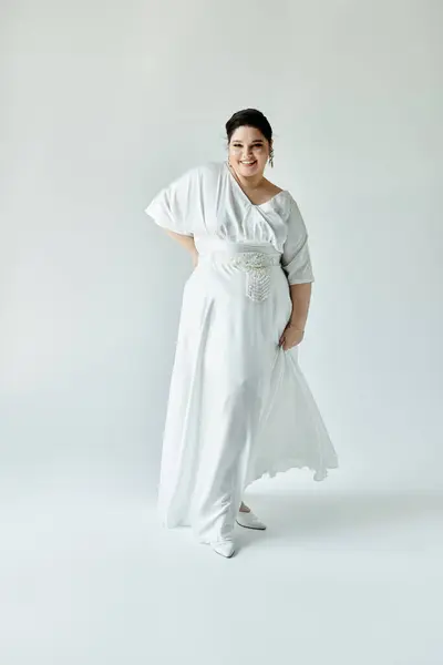 Stock image A beautiful plus size bride showcases her elegance in a flowing white wedding dress with sparkling earrings.