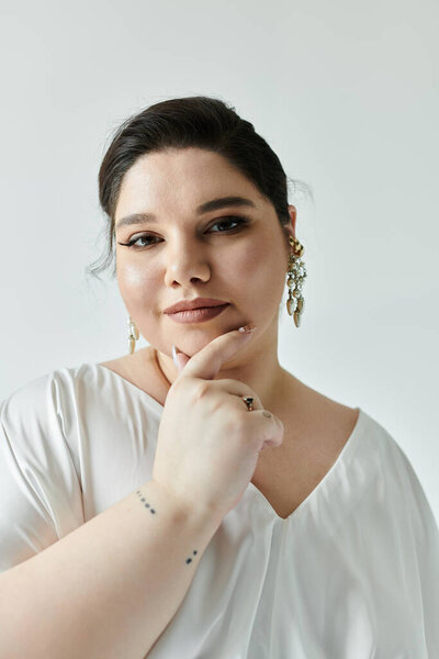 Красивая невеста плюс размер демонстрирует свою сияющую элегантность, украшенную вечным свадебным платьем и мерцающими сережками.