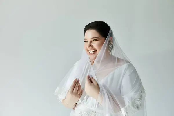 stock image A joyful bride in a graceful white gown shines with elegance, adorned with beautiful earrings and a veil.