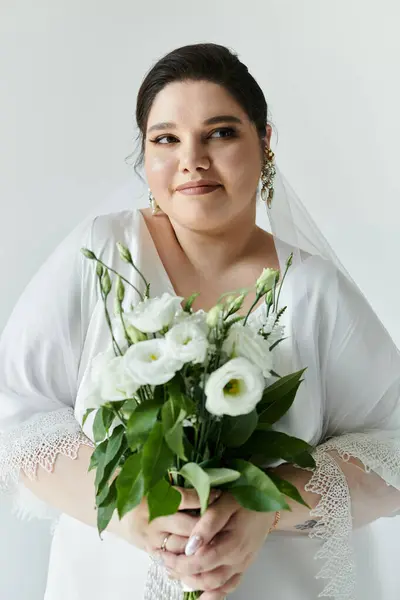 stock image A beautiful plus-size bride embraces her bouquet, exuding elegance and joy on her special day.