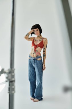 Modaya uygun bir kadın günlük kıyafetleriyle poz verirken dövmelerini sergiler..