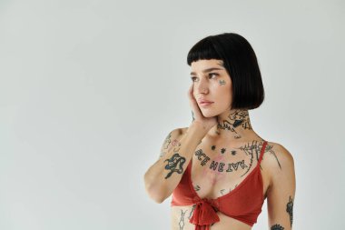 Dövmeleri olan genç bir kadın düşüncelere dalmışken şık görünüşünü sergiliyor..