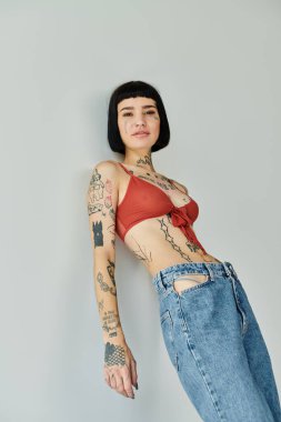 Şık bir kadın, sade bir arkaplana karşı özgüvenle poz verir..