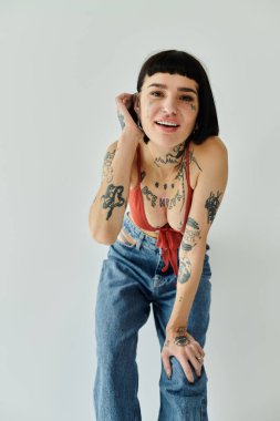 Şık giyinmiş güzel bir kadın şakacı pozlar veriyor, dövmelerini gösteriyor..