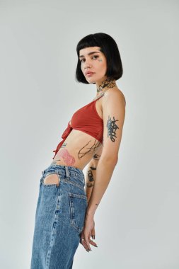 A fashionable woman shows off her tattoos while posing confidently. clipart