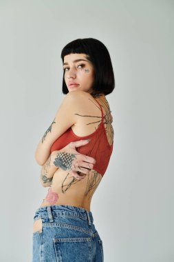 Şık bir kadın kendine güvenerek poz verir, dövmelerini ve kıyafetlerini çizer..