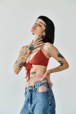 Genç bir kadın kendine güvenerek modellik yapıyor. Dövmelerle süslenmiş şık bir kıyafet..