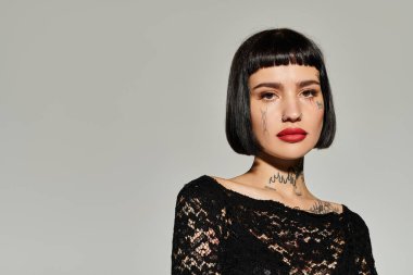 Genç bir kadın moda kıyafetlerine güveniyor, dövmelerini sergiliyor..