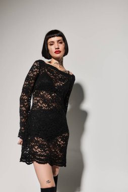 Çekici genç bir kadın zarif dantel kıyafetlerle poz verirken dövmelerini sergiliyor..