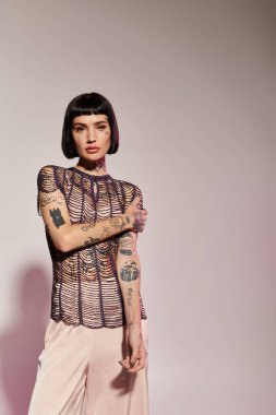 A young woman with striking tattoos poses confidently in fashionable clothing. clipart