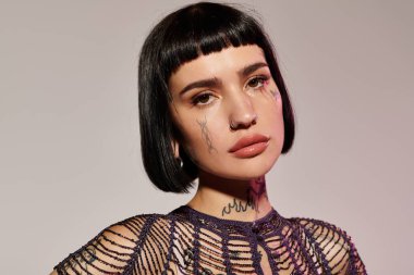 Genç bir kadın kendine güvenerek dövmelerini ve şık giysilerini sergiliyor..