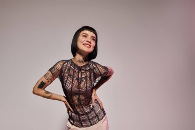 A young woman showcases her unique style with tattoos and flair. clipart