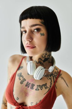 A stylish young woman showcases her tattoos while wearing headphones. clipart