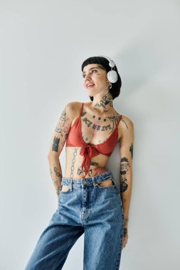 Dövmeli genç bir kadın müzik dinlerken kendine güvenen bir poz verir..