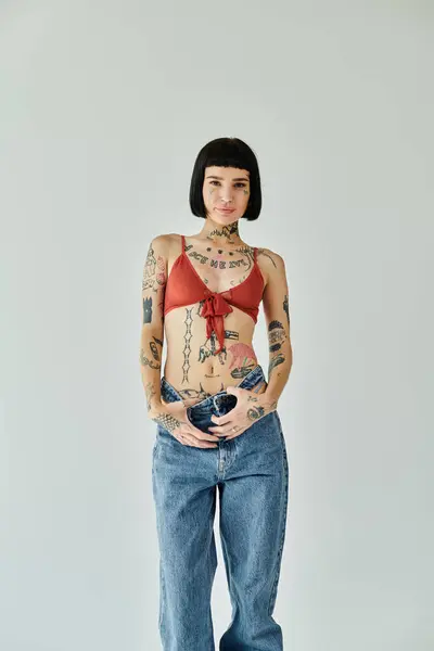 stock image A stylish young woman with tattoos strikes a pose, expressing her individuality.