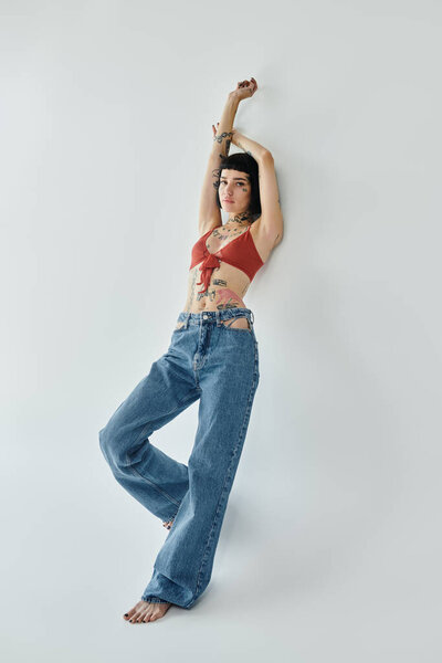 Модная женщина позирует элегантно, подчеркивая свои татуировки и уникальный стиль.