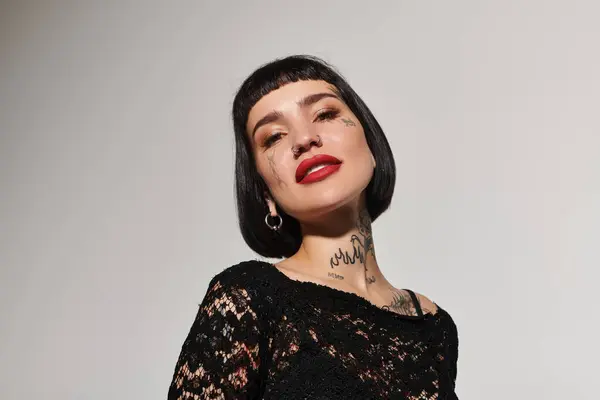 stock image Stylish woman showcases unique tattoos and modern fashion in elegant lighting.