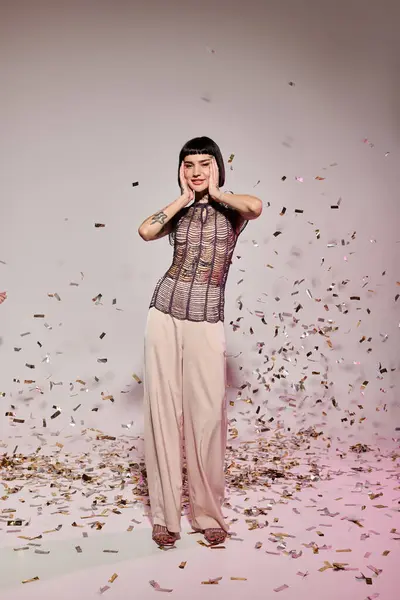 Stock image A stylish woman with tattoos enjoys a joyful moment in a celebratory atmosphere.