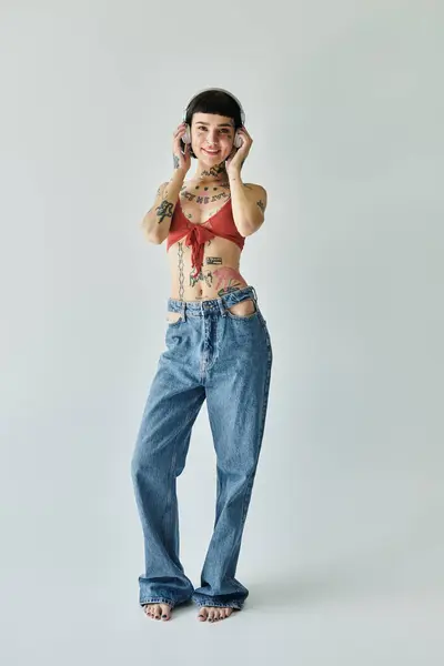 stock image A trendy young woman showcases her tattoos while smiling joyfully.