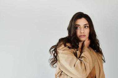 Genç bir kadın minimalist bir stüdyo ortamında zahmetsizce ışıldayan bir sonbahar elbisesi ve sıcaklığı sergiliyor..